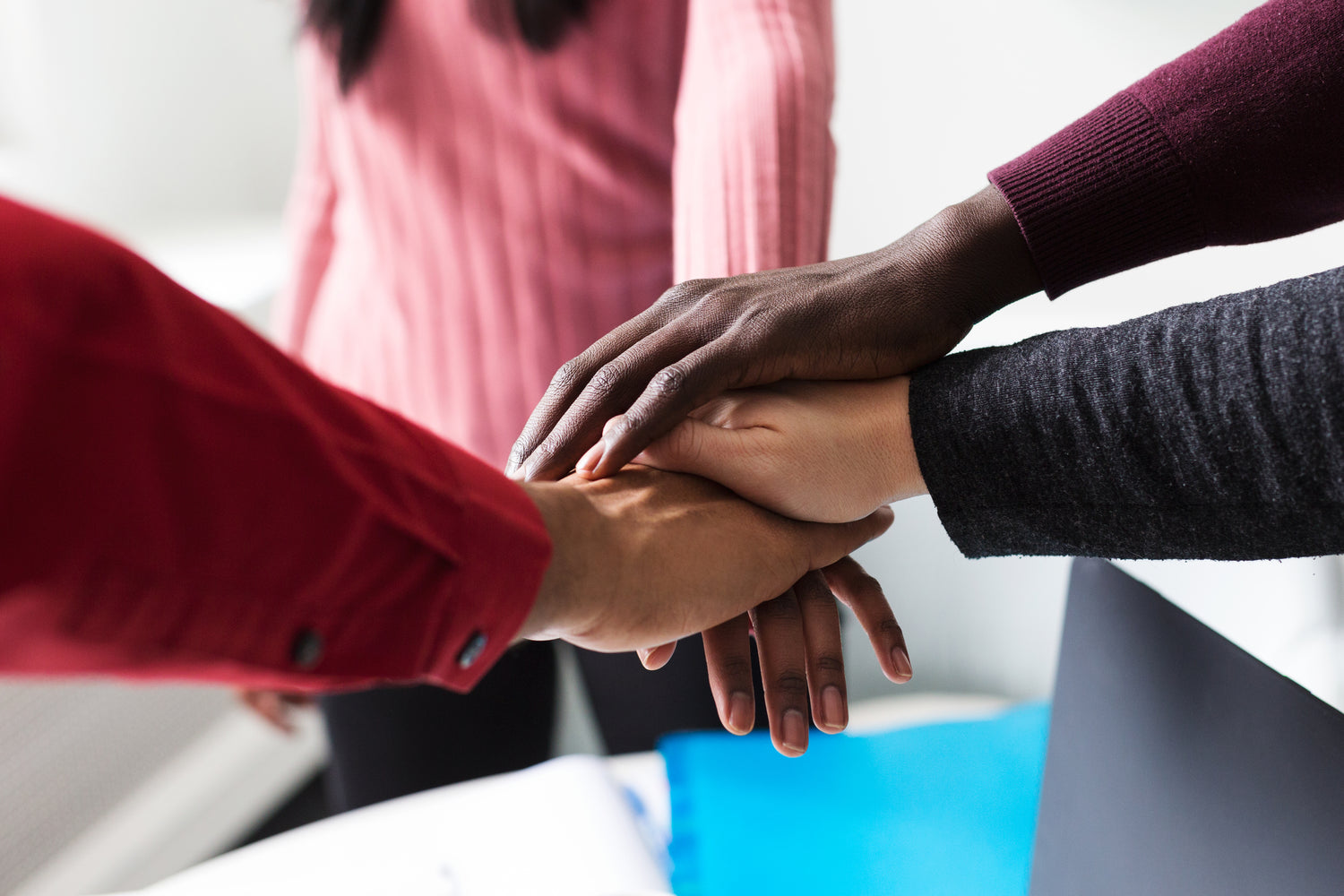 team members put their hands together in a circle to show solidarity with one another