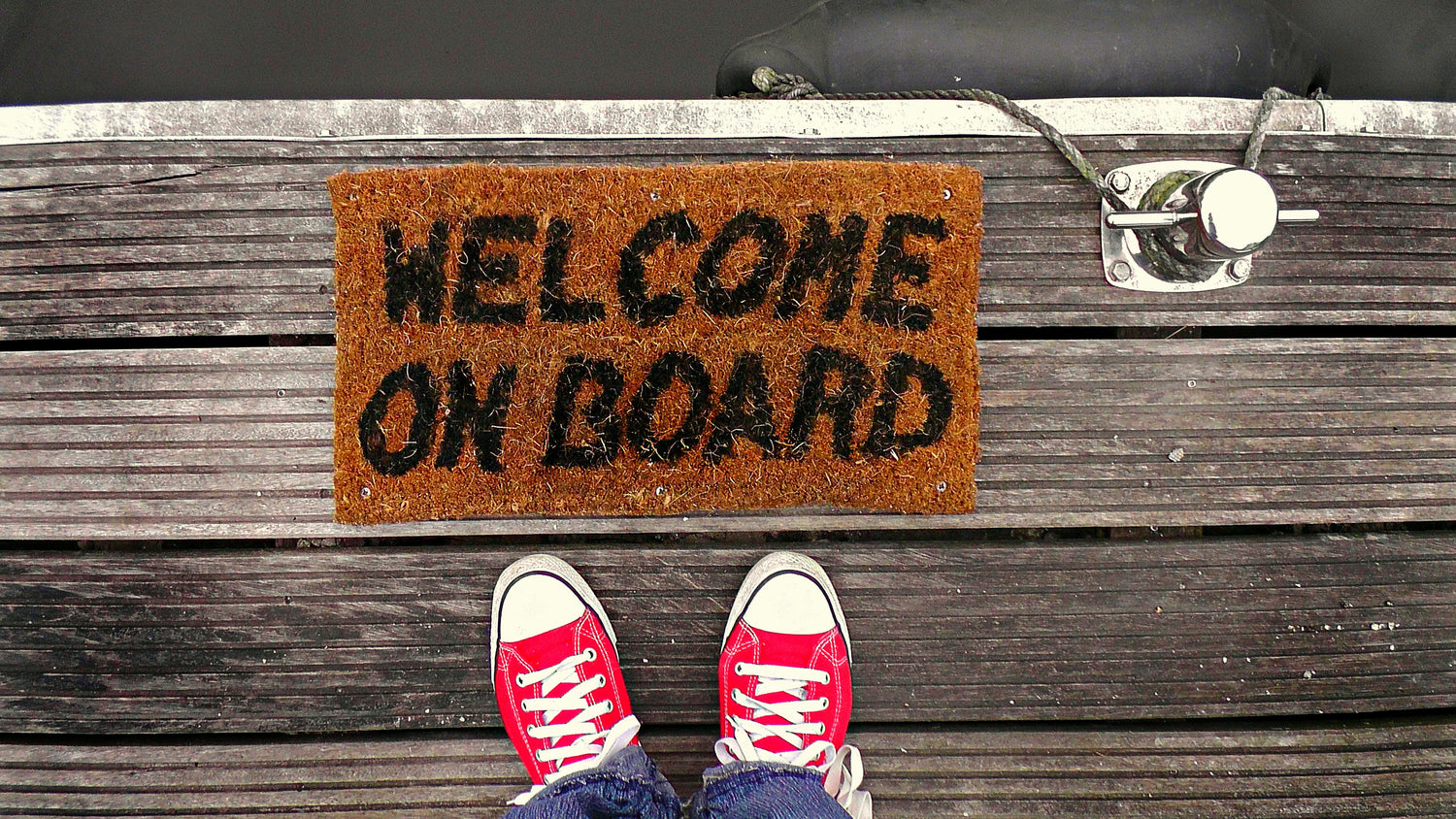 POV photo of dock floor mat which reads "Welcome on board". Photo by Mabel Amber